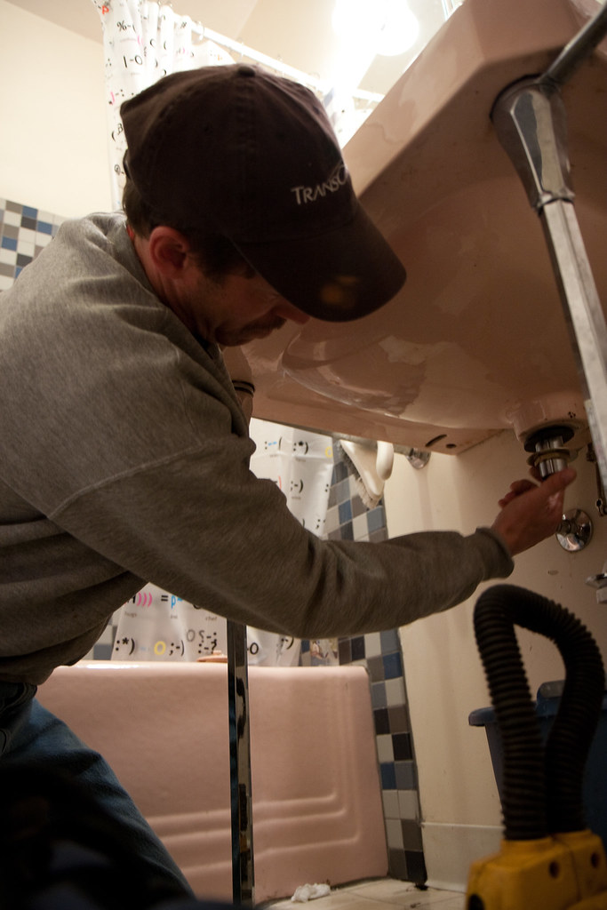 Plumber servicing pipework under a bathroom sink